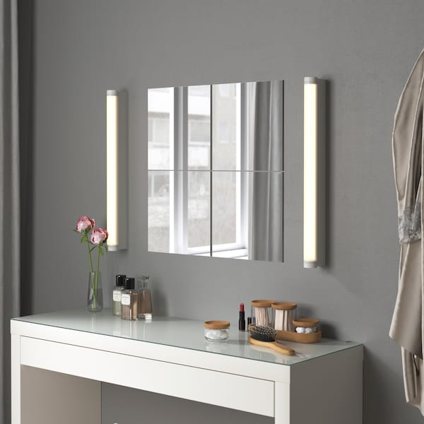 Four square BLODLÖNN mirrors are bookended by two vertical wall lamps above a white getting ready table/vanity area.