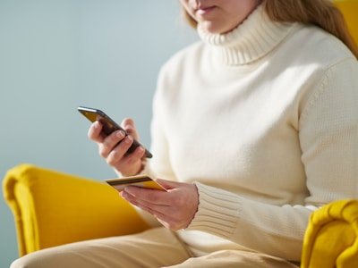 Ženska v rokah drži plačilno kartico in telefon