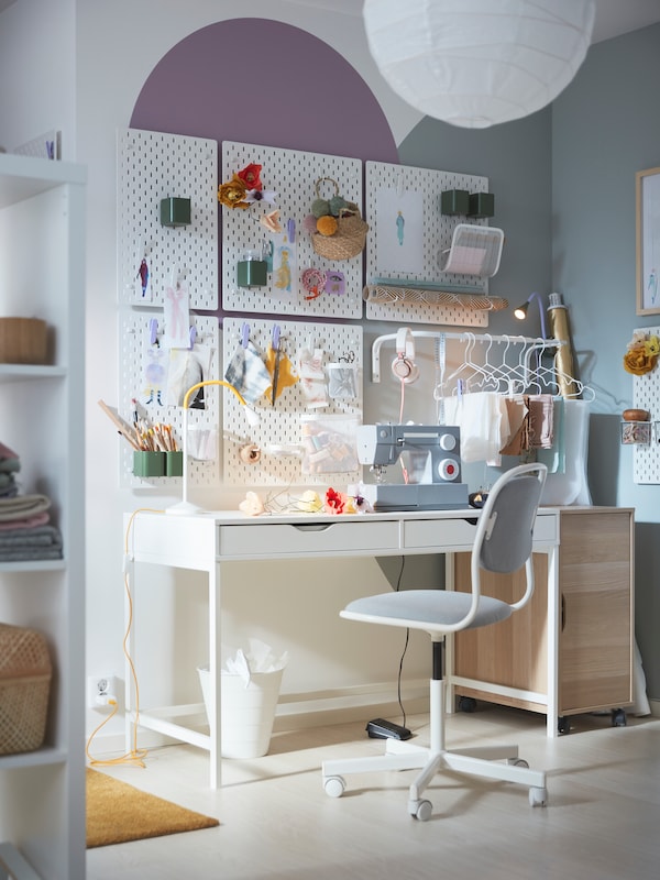 A light corner with an ÖRFJÄLL swivel chair by a white AXEL desk, above which hangs a neat arrangement of SKÅDIS pegboards.