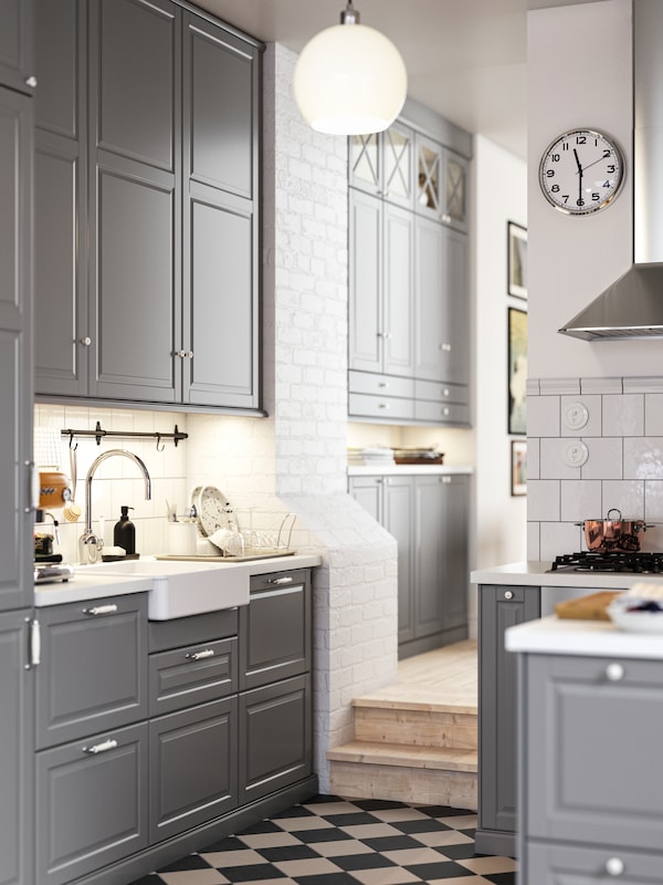 A kitchen with grey BODBYN fronts and a white HAVSEN sink bowl with visible front leading into a hallway with more cabinets.