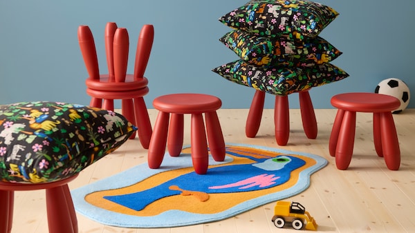 Six red children’s stools, a bright coloured toucan rug and colourful cushions with jungle theme.