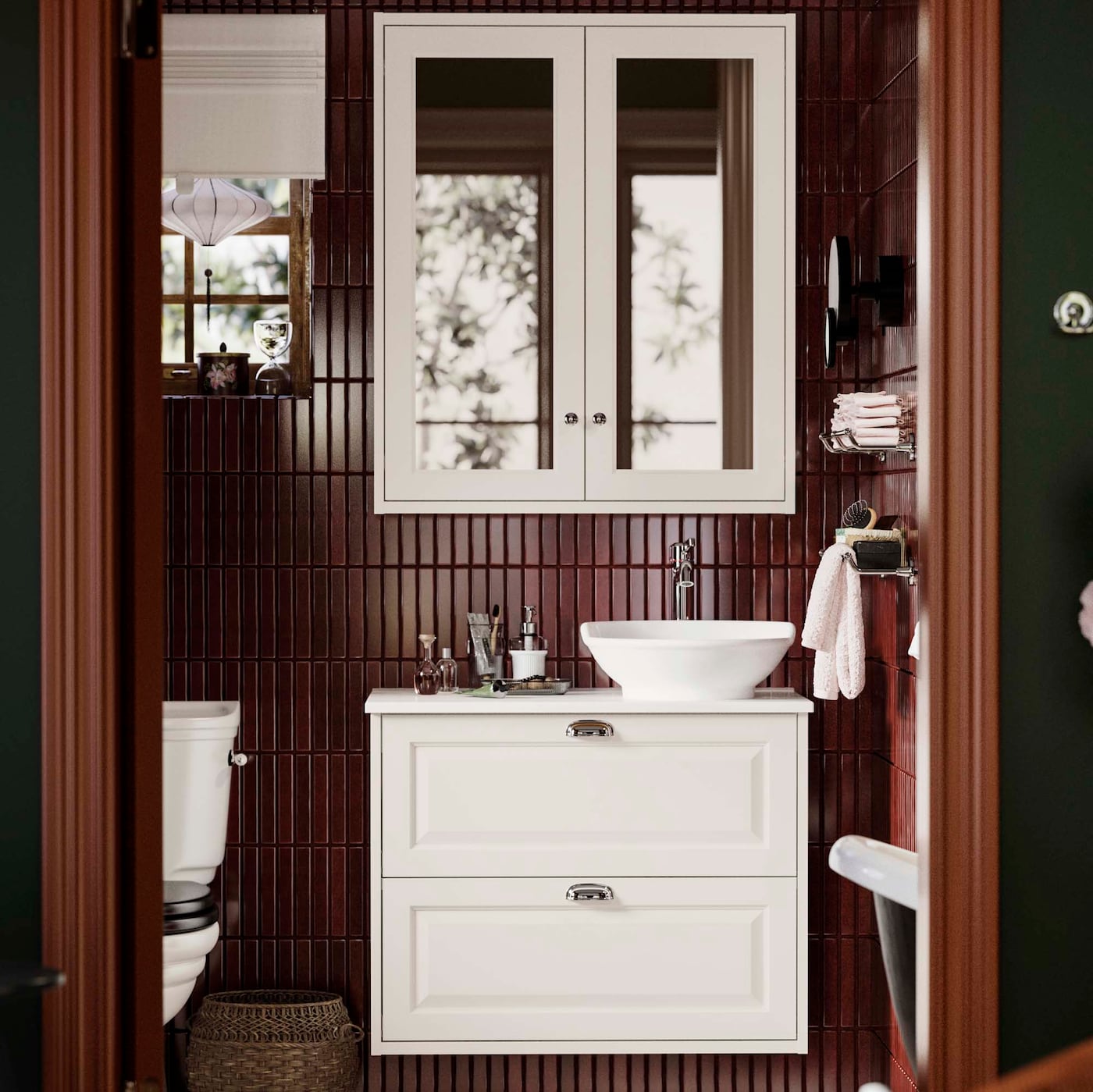 A bathroom cabinet and washstand in view in a dark tiled bathroom.